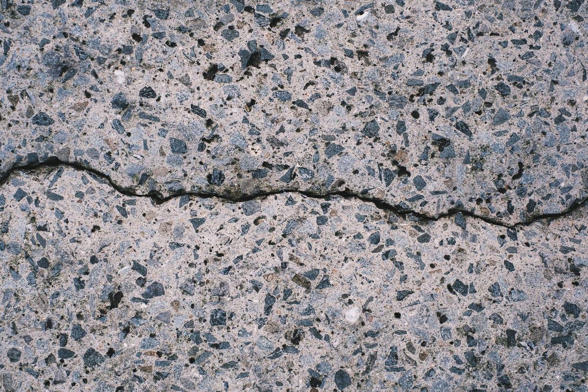 Cracked exposed aggregate driveway surface needing resin resurfacing